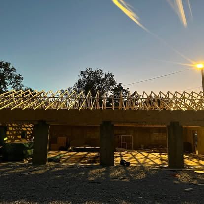Roof trusses framed over a concrete-block structure at dusk
